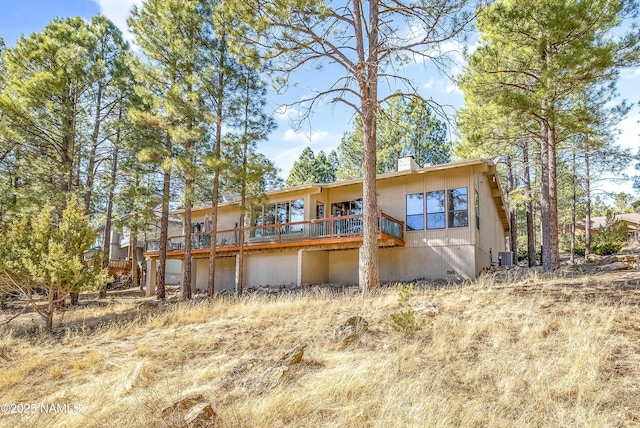 rear view of house with a deck, crawl space, a chimney, and central air condition unit