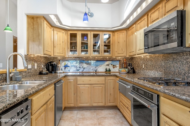 kitchen featuring appliances with stainless steel finishes, dark stone counters, glass insert cabinets, and a sink