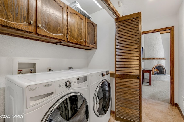 washroom featuring light tile patterned flooring, light colored carpet, separate washer and dryer, a fireplace, and cabinet space