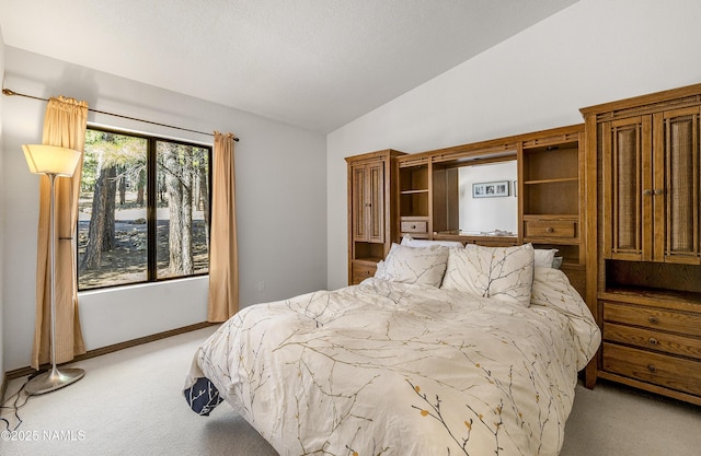 bedroom with lofted ceiling, light carpet, baseboards, and a textured ceiling