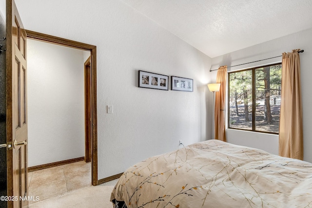 bedroom featuring a textured wall, vaulted ceiling, a textured ceiling, and baseboards