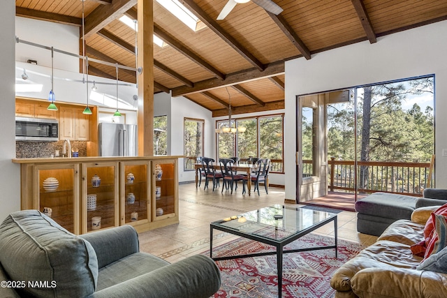 sunroom featuring vaulted ceiling with skylight, wood ceiling, a sink, and ceiling fan with notable chandelier