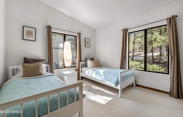 bedroom with vaulted ceiling, baseboards, and light colored carpet