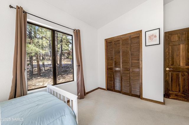 bedroom featuring lofted ceiling, a closet, light carpet, and baseboards