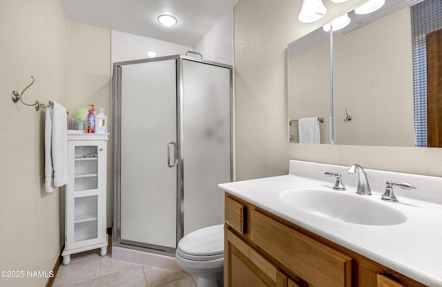 bathroom with a stall shower, vanity, toilet, and tile patterned floors