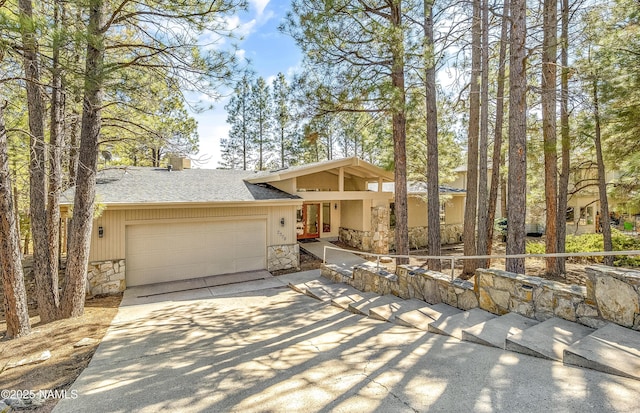 view of front of property with an attached garage, stone siding, concrete driveway, roof with shingles, and a chimney