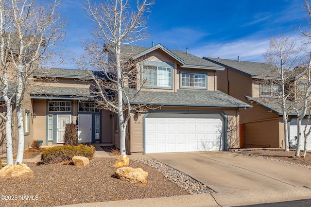 traditional-style house featuring a garage, roof with shingles, and driveway