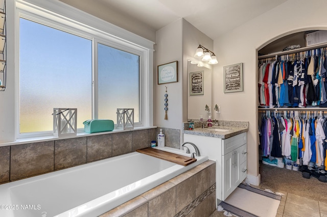 bathroom with tile patterned floors, vanity, and tiled bath