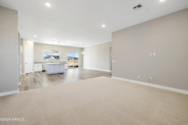 unfurnished living room featuring light colored carpet and sink