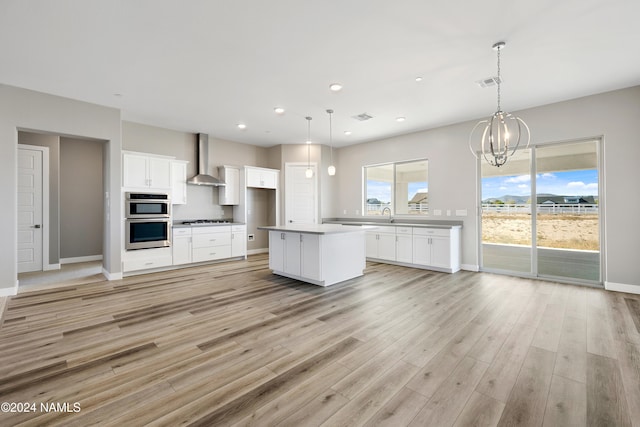 kitchen with white cabinets, gas cooktop, a center island, and wall chimney exhaust hood