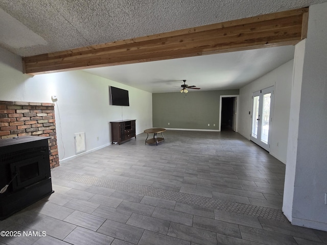 5895 Timberline Trl, Flagstaff, AZ 86004 - unfurnished living room featuring baseboards, a wood stove, a ceiling fan, and beam ceiling