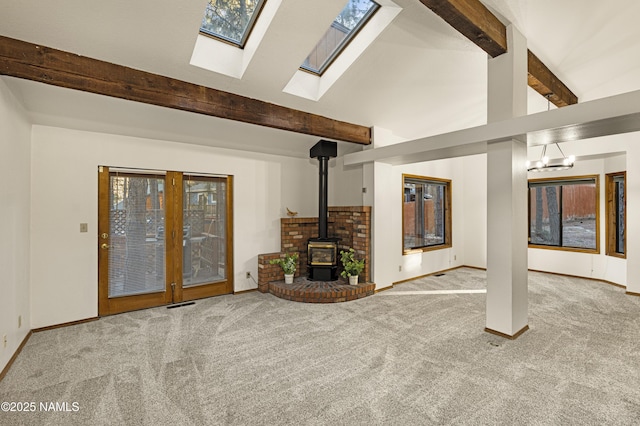 unfurnished living room with light colored carpet, beamed ceiling, high vaulted ceiling, and a wood stove