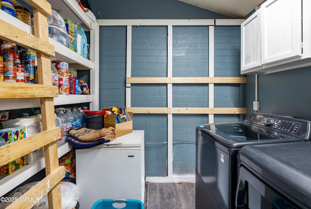 laundry area with wood finished floors, concrete block wall, cabinet space, and independent washer and dryer