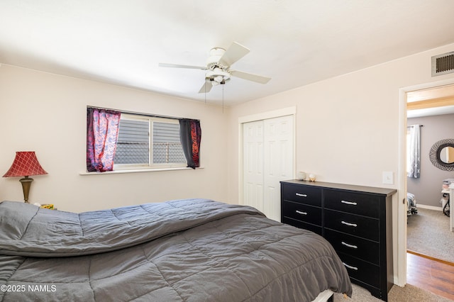 bedroom with visible vents, baseboards, ceiling fan, wood finished floors, and a closet