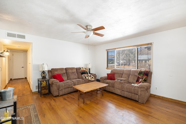 living area with ceiling fan, visible vents, baseboards, and hardwood / wood-style floors