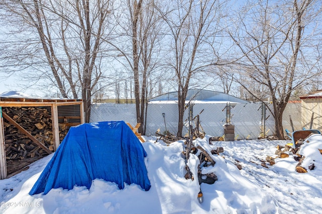 yard covered in snow with an outdoor structure and fence