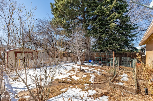 snowy yard featuring a vegetable garden, a shed, an outdoor structure, and a fenced backyard