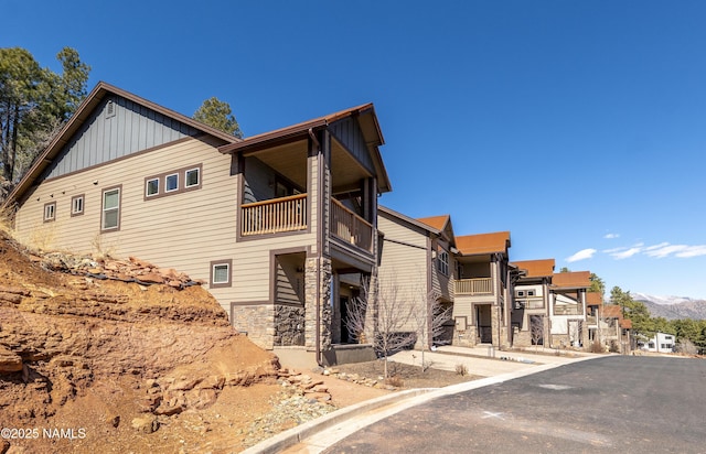 view of side of property with a balcony, board and batten siding, and stone siding