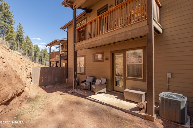 exterior space with a balcony, cooling unit, and fence