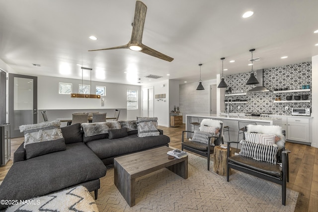 living area with light wood finished floors, visible vents, recessed lighting, and ceiling fan