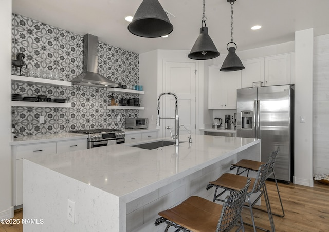 kitchen with open shelves, a sink, decorative backsplash, stainless steel appliances, and wall chimney exhaust hood