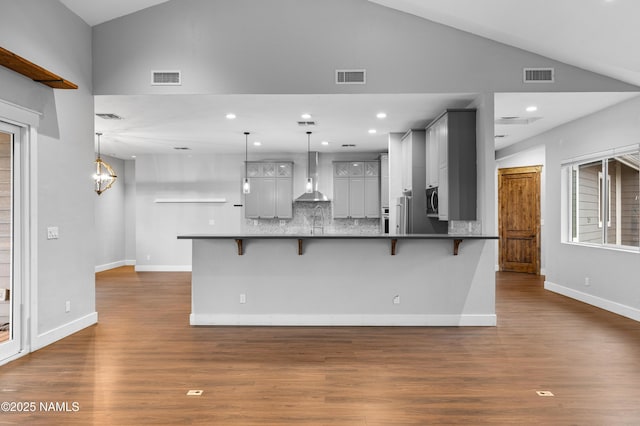 7497 W Dreamview Trl, Flagstaff, AZ 86001 - kitchen featuring wall chimney exhaust hood, vaulted ceiling, a breakfast bar area, appliances with stainless steel finishes, and dark wood finished floors
