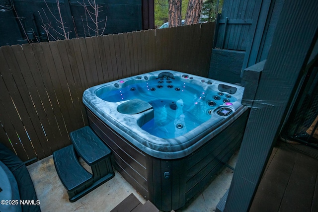 view of patio featuring an outdoor hot tub and fence