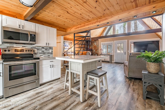 kitchen featuring open floor plan, light countertops, decorative backsplash, appliances with stainless steel finishes, and white cabinetry