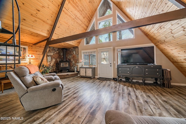 living room with beam ceiling, a healthy amount of sunlight, wood finished floors, and a wood stove