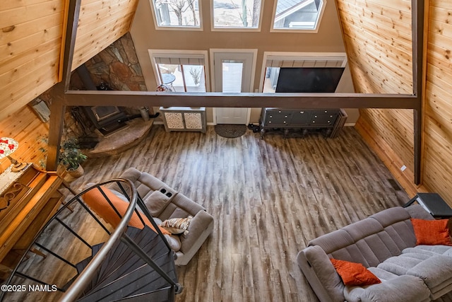 living area with plenty of natural light, wood finished floors, and a towering ceiling