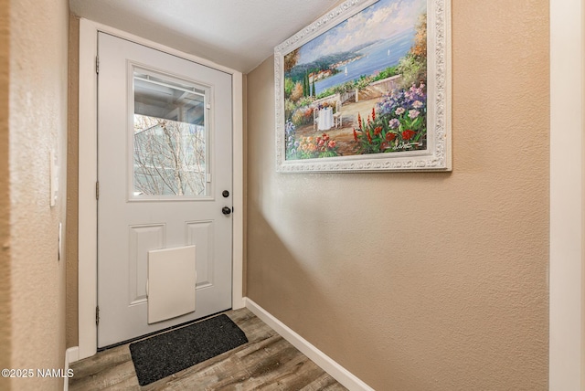 entryway featuring a textured wall, baseboards, and wood finished floors