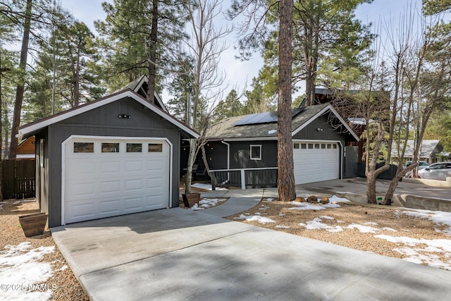 view of front of property featuring solar panels, concrete driveway, and fence