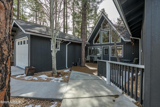 rear view of property featuring a garage and a wooden deck