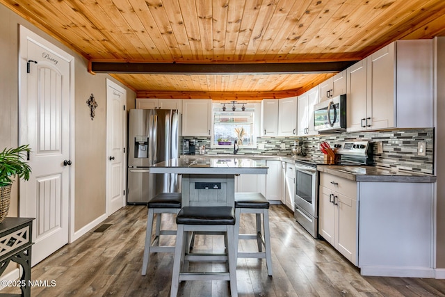 kitchen with a breakfast bar, decorative backsplash, stainless steel appliances, and beam ceiling