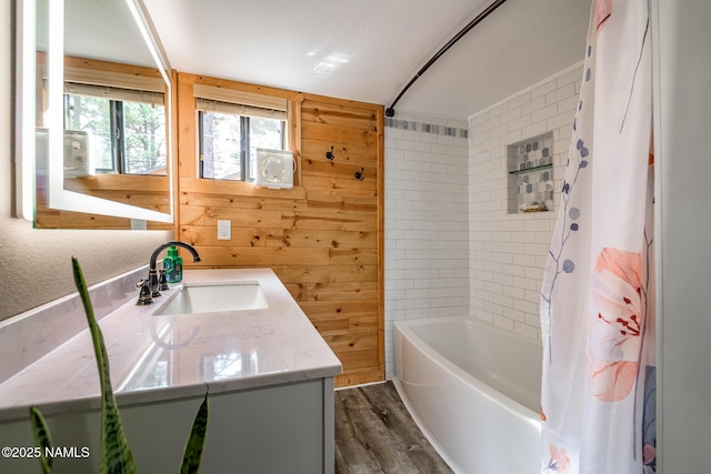 bathroom with vanity, shower / bathtub combination with curtain, wood finished floors, and wood walls