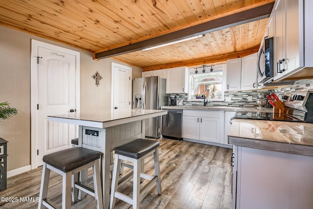 kitchen with tasteful backsplash, light wood finished floors, a kitchen bar, stainless steel appliances, and a sink