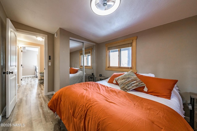 bedroom with a closet, baseboards, lofted ceiling, and light wood-style floors