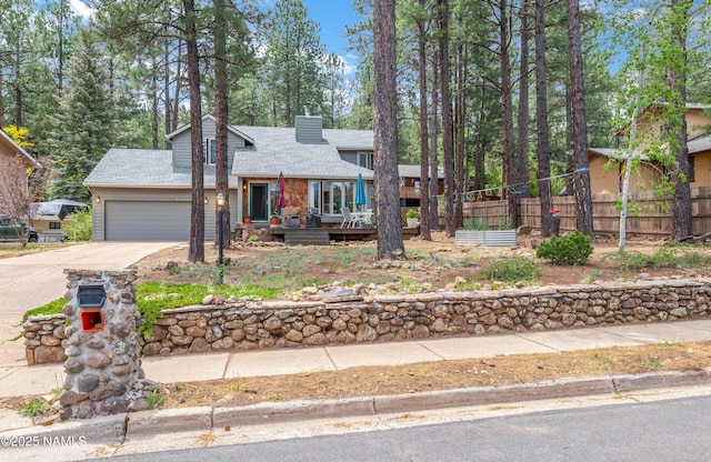 2606 N Fremont Blvd, Flagstaff, AZ 86001 - view of front of house featuring concrete driveway, a garage, a shingled roof, a chimney, and a wooden deck