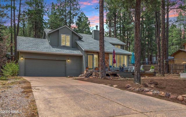 2606 N Fremont Blvd, Flagstaff, AZ 86001 - view of front facade featuring a shingled roof, a chimney, concrete driveway, covered porch, and an attached garage