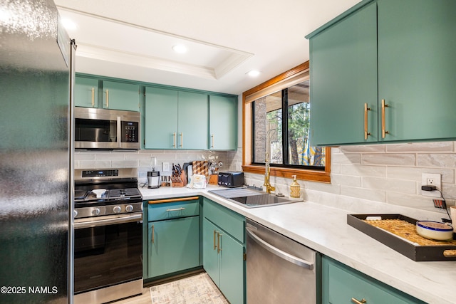 kitchen with tasteful backsplash, appliances with stainless steel finishes, light countertops, a sink, and a raised ceiling
