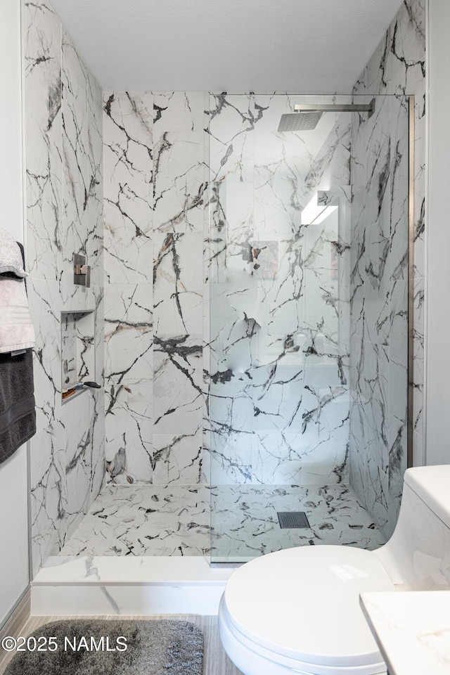 full bath with a marble finish shower and toilet