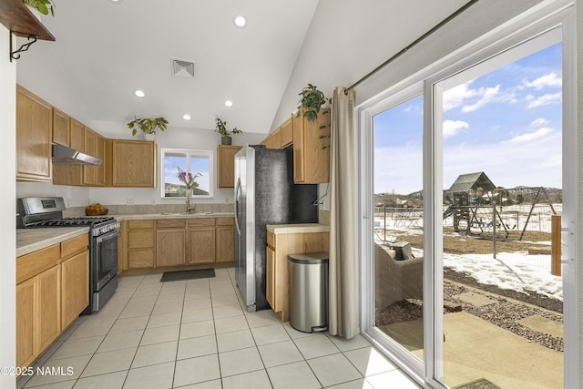 kitchen featuring visible vents, under cabinet range hood, lofted ceiling, light tile patterned floors, and appliances with stainless steel finishes