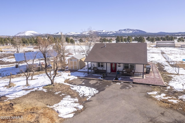 view of front of property with a storage unit, an outbuilding, driveway, fence, and a mountain view