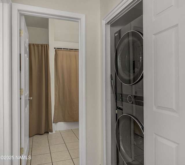 washroom with laundry area, stacked washer and dryer, and light tile patterned flooring