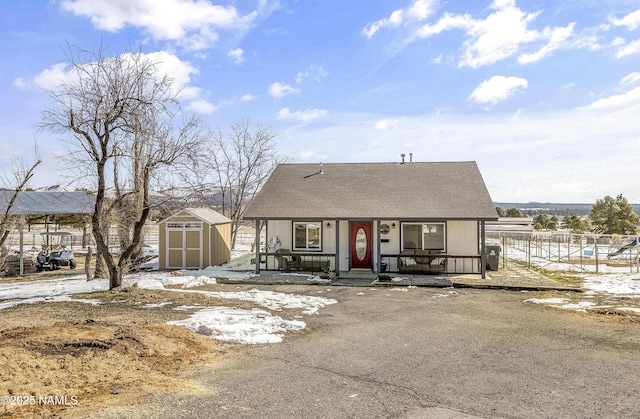 view of front of property with fence, a shed, a porch, a shingled roof, and an outdoor structure