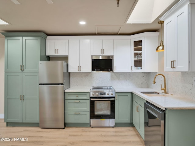 425 W Rte 66, Williams, AZ 86046 - kitchen with appliances with stainless steel finishes, pendant lighting, white cabinetry, sink, and light hardwood / wood-style floors