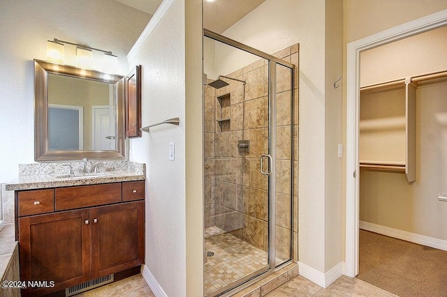 bathroom with tile patterned flooring, a shower with shower door, and vanity