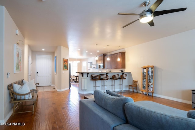 living room featuring light hardwood / wood-style floors and ceiling fan with notable chandelier