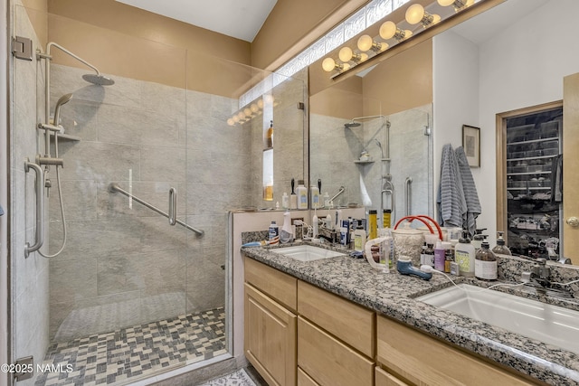 full bath featuring a sink, a shower stall, and double vanity