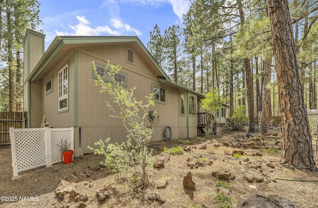view of property exterior featuring fence and a chimney